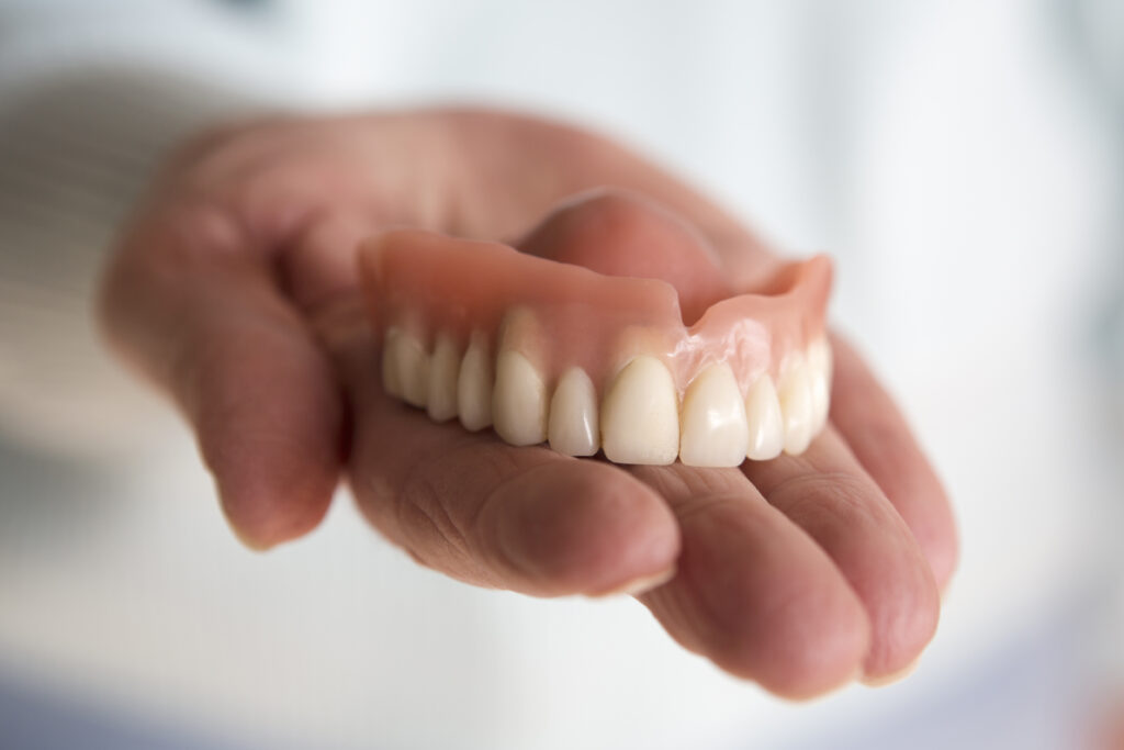 closeup of older woman's hand holding a teeth denture