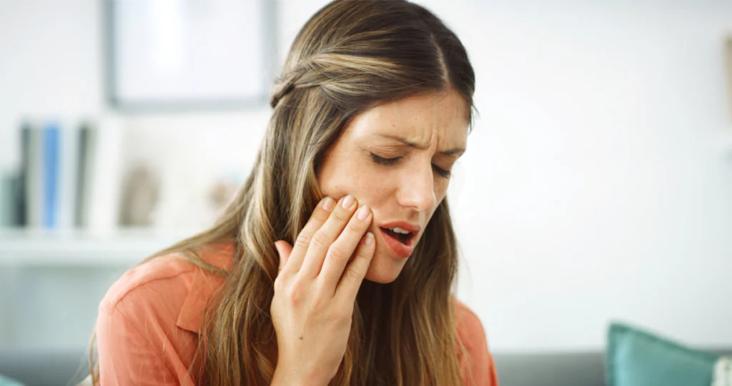 A young woman holding her jaw because of tooth pain