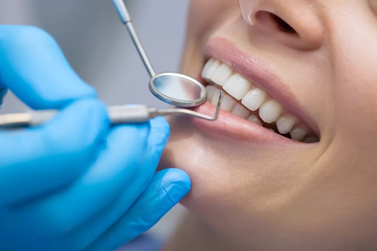 A person’s smile with a dentist holding tools up to their teeth in El Paso.