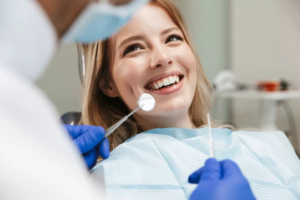 A woman smiling at a dentist holding up dental tools in El Paso.